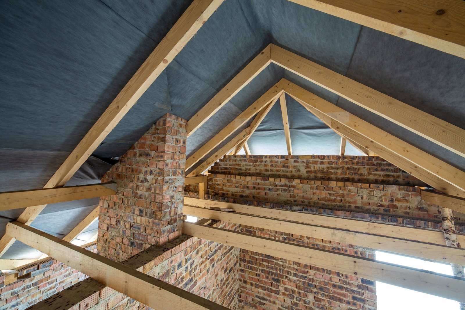 Grenier d'un bâtiment en construction avec poutres en bois d'une structure de toit et murs en briques